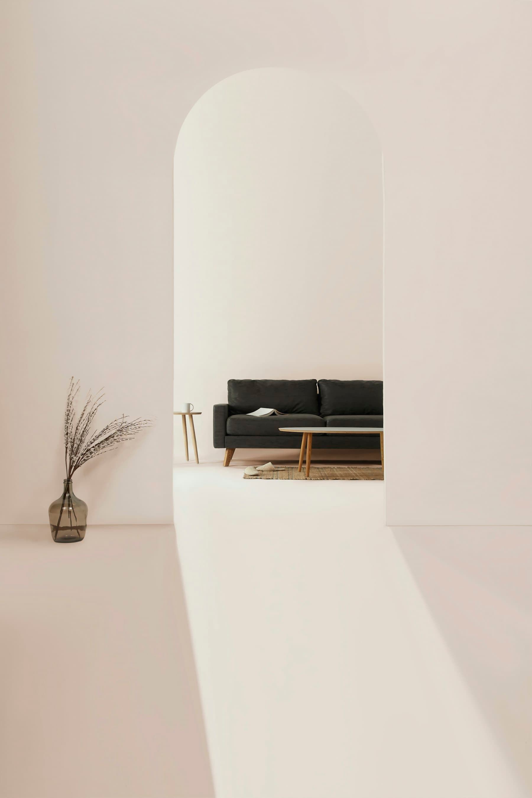A dark sofa seen through a pale arched opening in a quiet room