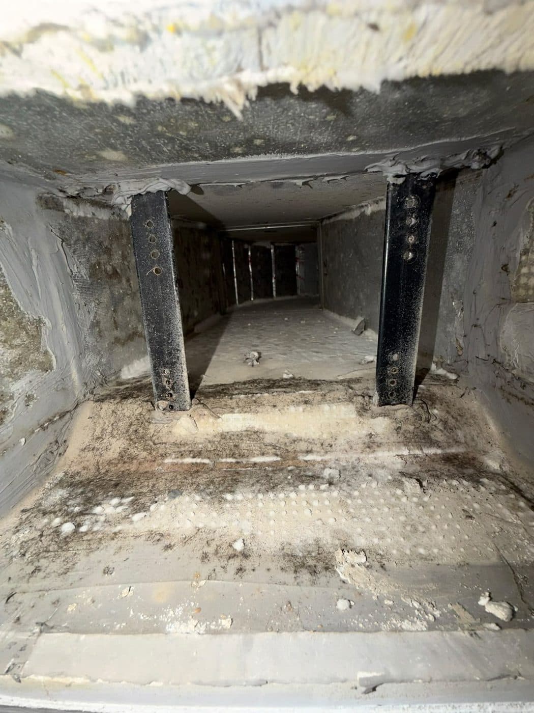 Before: the inside of an AC duct coated in dust with dark mould-like spotting