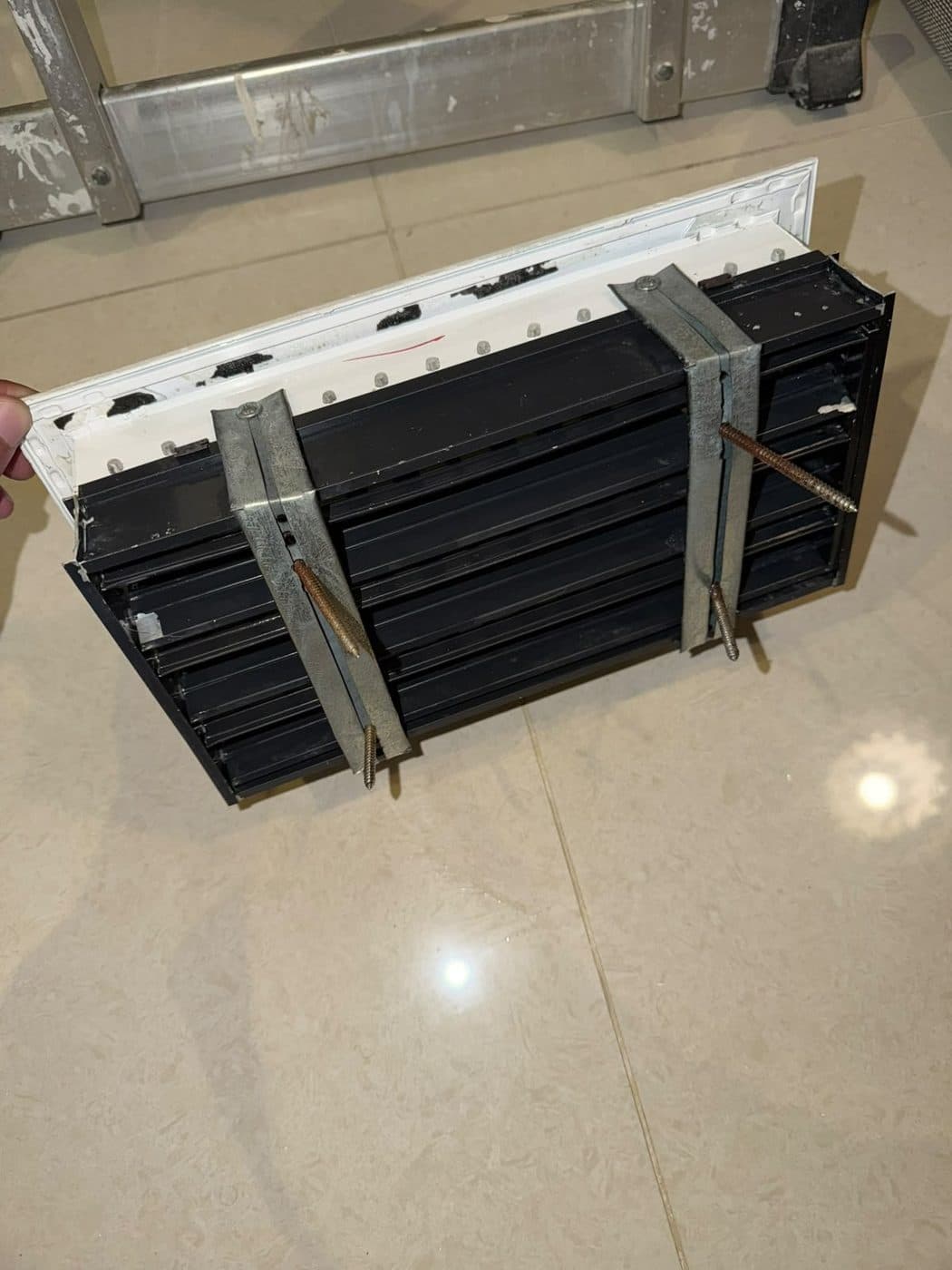 After: the same AC grille cleaned, its slats back to black and the frame white